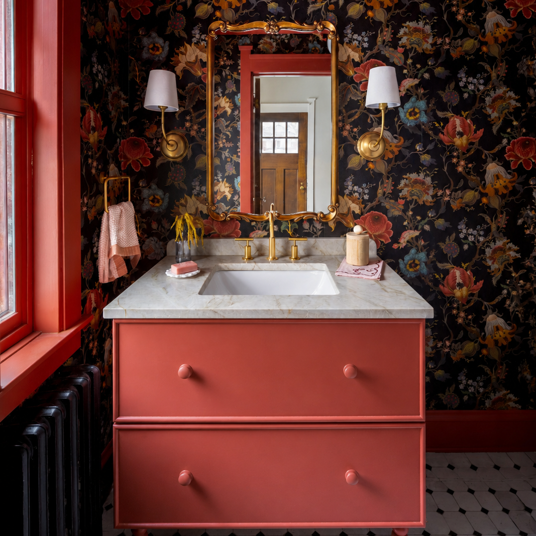 Bathroom with red vanity, floral wallpaper, and decorative elements.